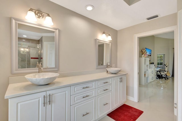 bathroom with a sink, double vanity, visible vents, and a shower with door