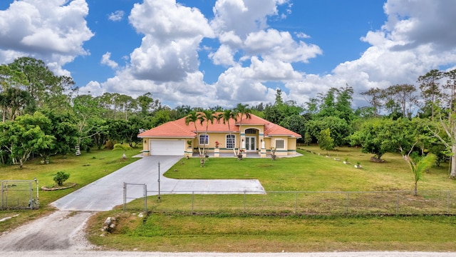 mediterranean / spanish-style home featuring fence, driveway, a garage, stucco siding, and a front lawn