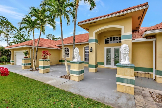 view of front facade with stucco siding, french doors, a tile roof, and a garage