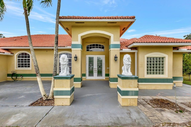 property entrance with stucco siding, french doors, and a tiled roof