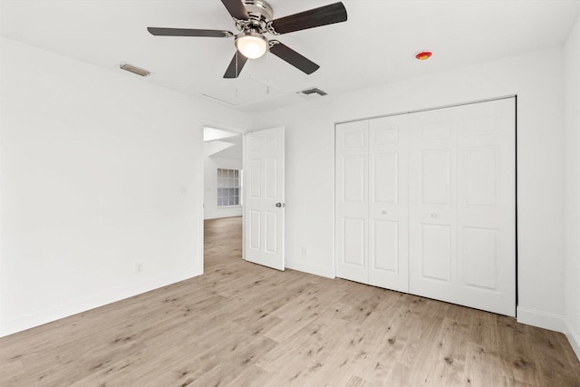 unfurnished bedroom featuring baseboards, visible vents, wood finished floors, and a closet