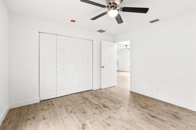 unfurnished bedroom featuring baseboards, wood finished floors, visible vents, and a closet
