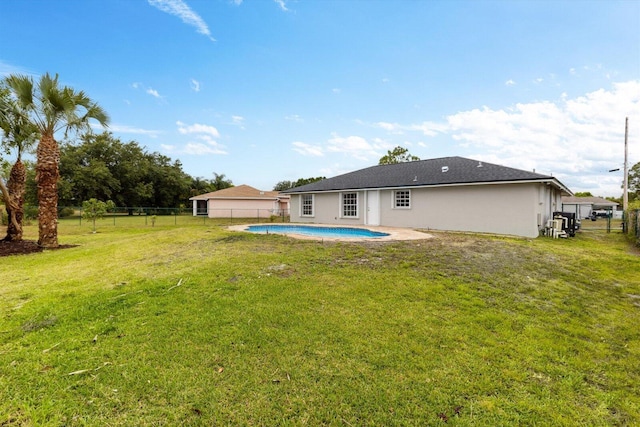 rear view of house with fence, a fenced in pool, and a lawn