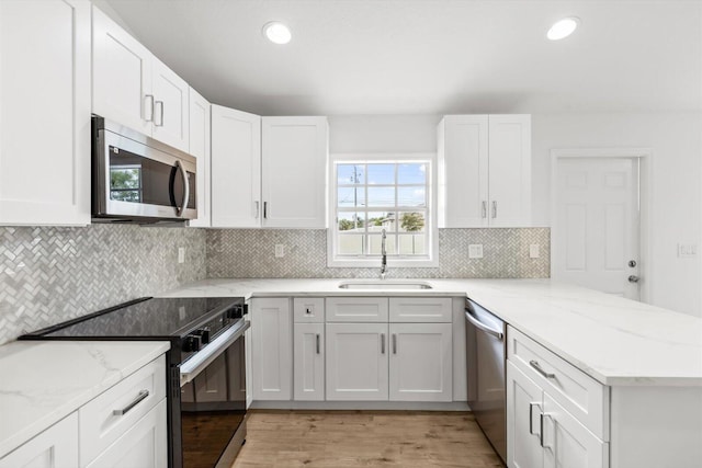 kitchen featuring a sink, white cabinets, appliances with stainless steel finishes, and a peninsula
