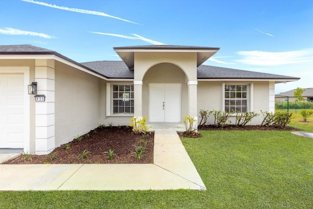 property entrance featuring a lawn, stucco siding, a shingled roof, and a garage