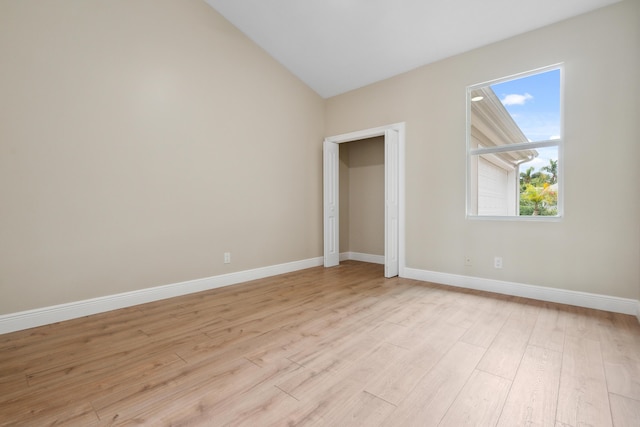 unfurnished bedroom featuring baseboards, lofted ceiling, and light wood-style floors