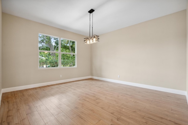 spare room featuring baseboards and light wood-type flooring