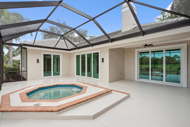 back of house featuring stucco siding, an in ground hot tub, a chimney, a ceiling fan, and a patio