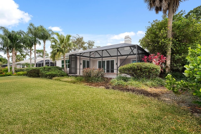 back of property featuring a lawn, a chimney, and glass enclosure