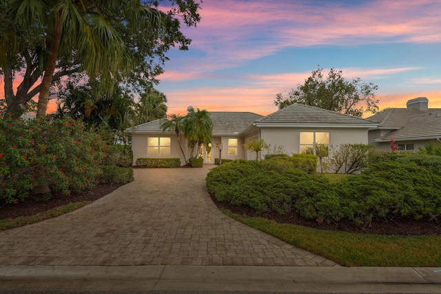 ranch-style house with decorative driveway, stucco siding, and a tiled roof