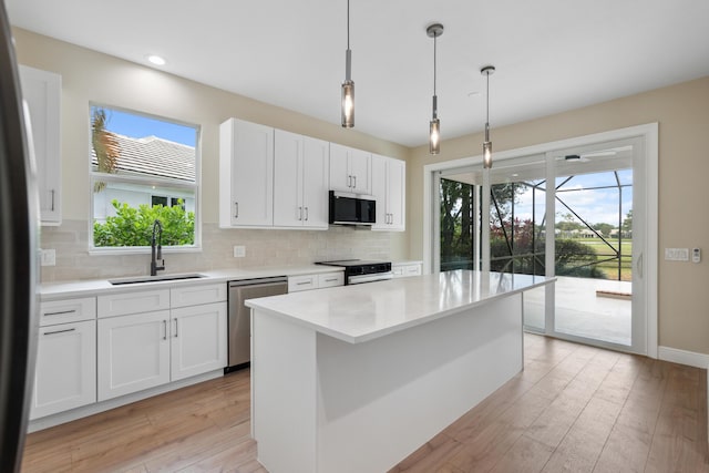 kitchen with light countertops, stainless steel appliances, decorative backsplash, and a sink