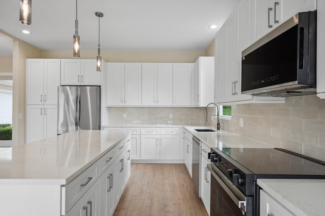 kitchen with stainless steel appliances, plenty of natural light, a sink, and light wood-style flooring