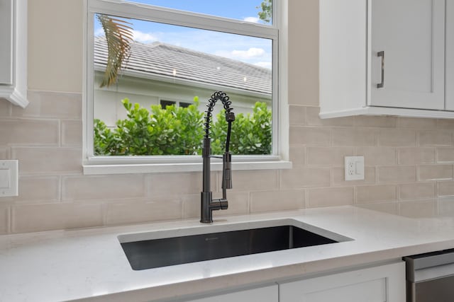 details with a sink, light stone countertops, backsplash, and white cabinetry