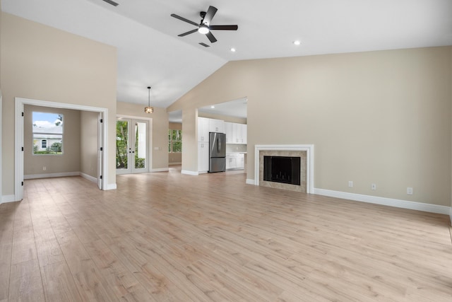 unfurnished living room with light wood-style floors, high vaulted ceiling, ceiling fan, and baseboards