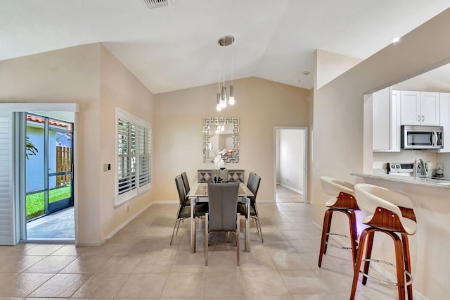 dining area featuring healthy amount of natural light, lofted ceiling, light tile patterned floors, and baseboards