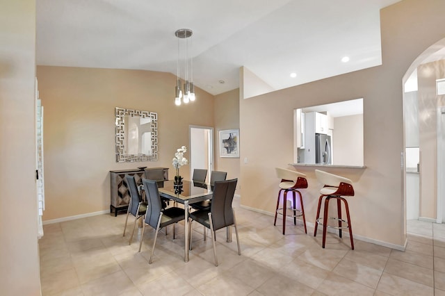 dining space featuring lofted ceiling, baseboards, arched walkways, and light tile patterned floors