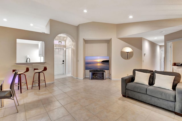 living area featuring lofted ceiling, baseboards, arched walkways, light tile patterned floors, and recessed lighting