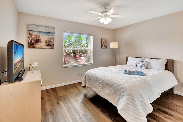 bedroom featuring wood finished floors, baseboards, and a ceiling fan