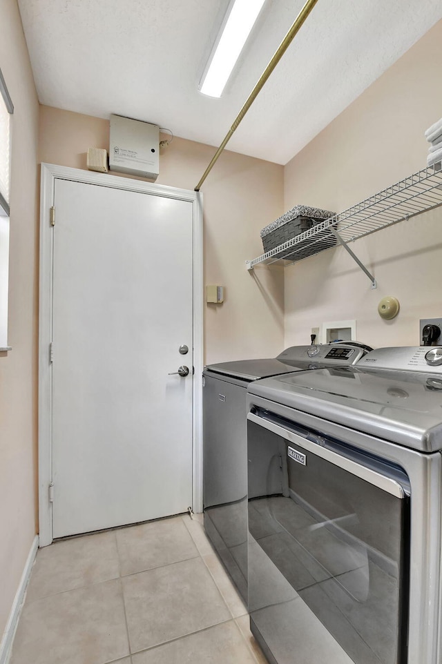 laundry room with washer and dryer, light tile patterned floors, and baseboards