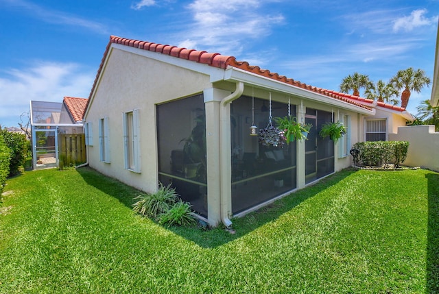 view of property exterior with a tiled roof, a sunroom, and stucco siding