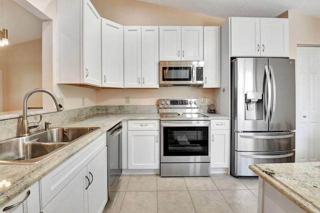 kitchen with stainless steel appliances, a sink, white cabinets, light tile patterned floors, and light stone countertops