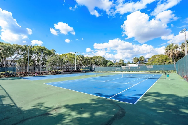 view of tennis court featuring fence and community basketball court