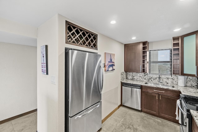 kitchen with a sink, open shelves, light stone counters, dark brown cabinetry, and appliances with stainless steel finishes