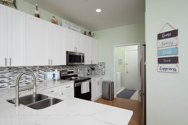 520 NW Galatone Ct, Port Saint Lucie, FL 34986 - kitchen featuring tasteful backsplash, a sink, light wood-style floors, stainless steel appliances, and white cabinetry
