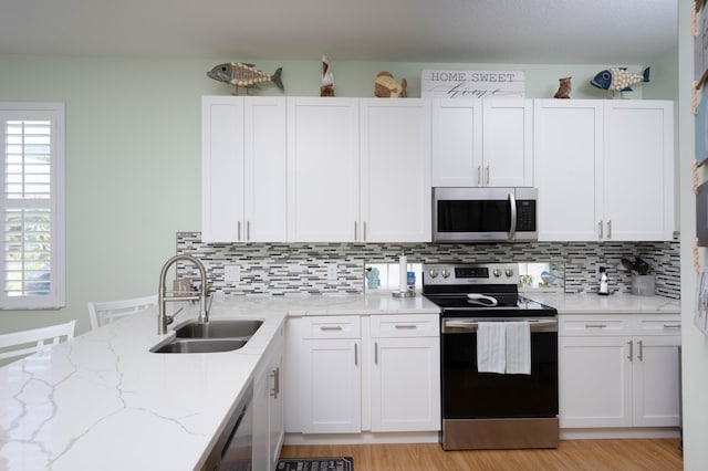 520 NW Galatone Ct, Port Saint Lucie, FL 34986 - kitchen featuring decorative backsplash, white cabinetry, light stone counters, a sink, and appliances with stainless steel finishes