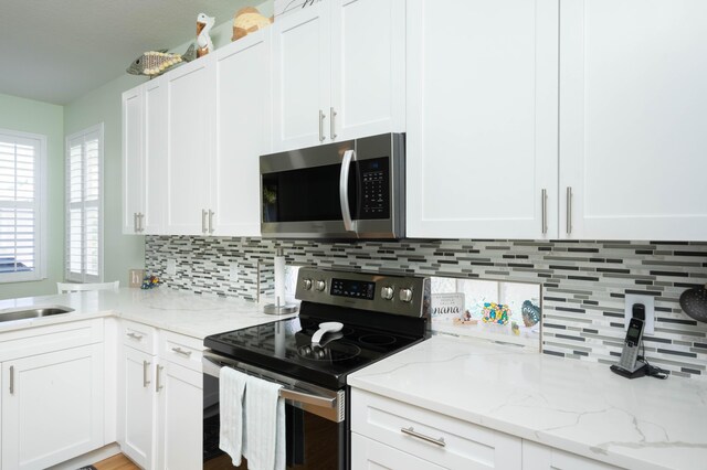 520 NW Galatone Ct, Port Saint Lucie, FL 34986 - kitchen with white cabinets, stainless steel appliances, light stone counters, and decorative backsplash
