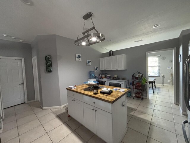 7746 99th Ct, Vero Beach, FL 32967 - kitchen with butcher block countertops, white cabinetry, baseboards, and light tile patterned flooring