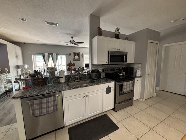 7746 99th Ct, Vero Beach, FL 32967 - kitchen with visible vents, a peninsula, white cabinetry, a sink, and appliances with stainless steel finishes