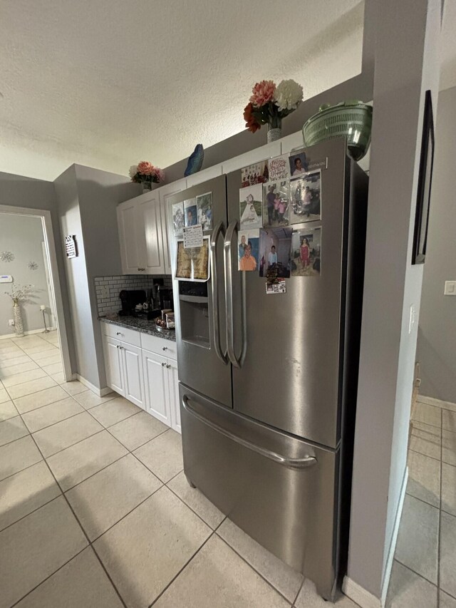 7746 99th Ct, Vero Beach, FL 32967 - kitchen with white cabinets, light tile patterned flooring, a textured ceiling, baseboards, and stainless steel refrigerator with ice dispenser