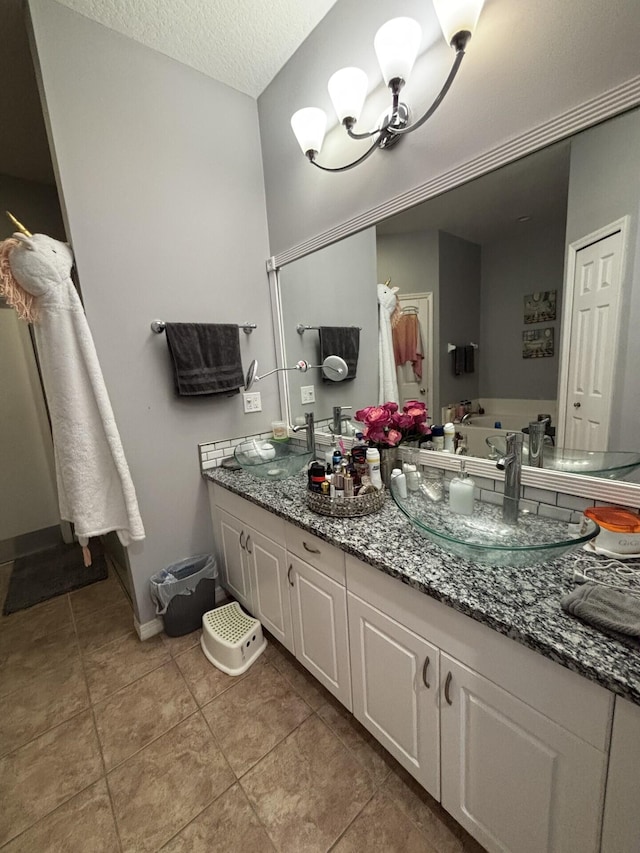 7746 99th Ct, Vero Beach, FL 32967 - bathroom with an inviting chandelier, vanity, a textured ceiling, tile patterned floors, and baseboards