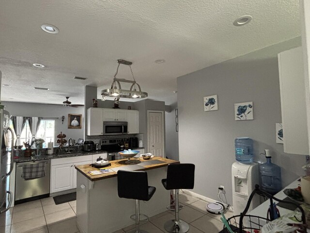 7746 99th Ct, Vero Beach, FL 32967 - kitchen with white cabinets, light tile patterned flooring, a sink, butcher block countertops, and stainless steel appliances