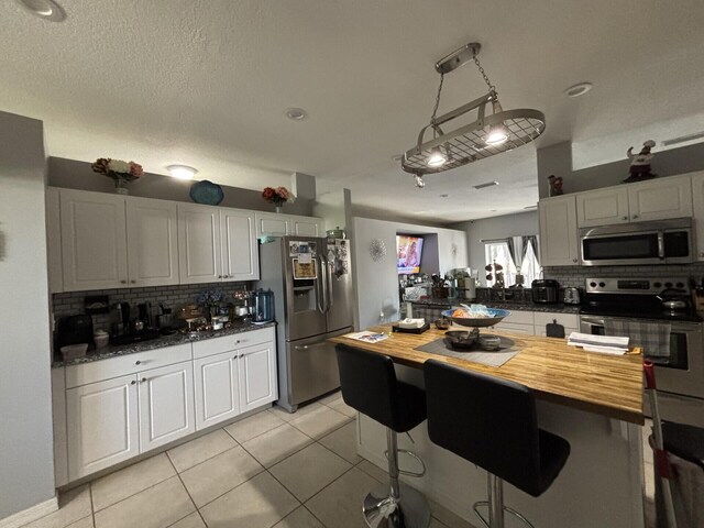 7746 99th Ct, Vero Beach, FL 32967 - kitchen with decorative backsplash, butcher block counters, a kitchen breakfast bar, and stainless steel appliances