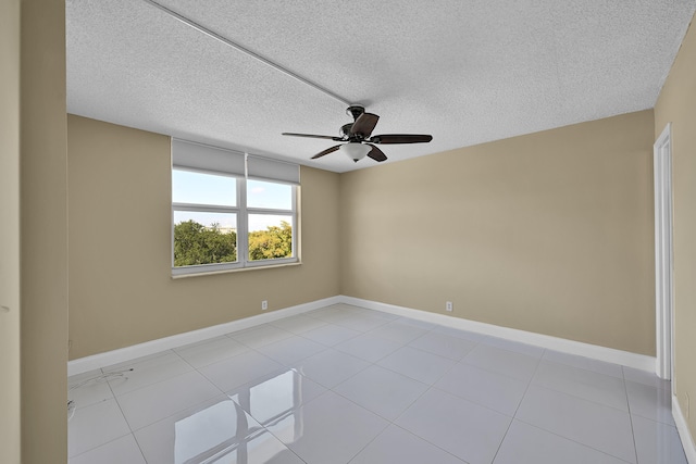 spare room with baseboards, a ceiling fan, a textured ceiling, and light tile patterned floors