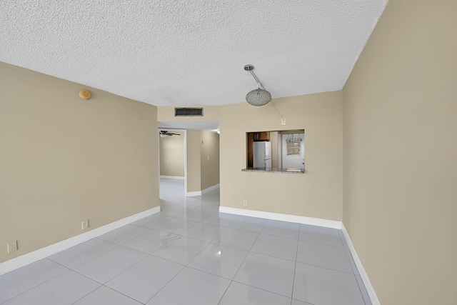 unfurnished room featuring visible vents, a textured ceiling, baseboards, and light tile patterned flooring