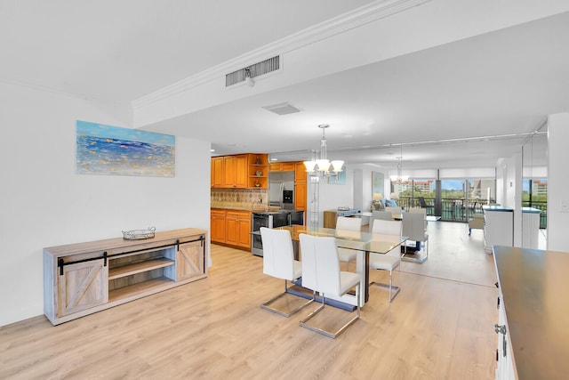 dining space featuring visible vents, light wood finished floors, crown molding, and a notable chandelier