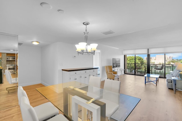 dining space with baseboards, light wood-type flooring, a chandelier, and visible vents