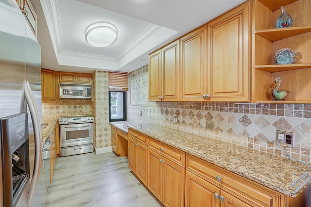 kitchen with appliances with stainless steel finishes, open shelves, light wood-style flooring, and a raised ceiling