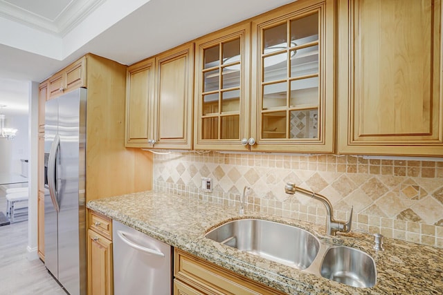 kitchen featuring light stone counters, a sink, decorative backsplash, and appliances with stainless steel finishes