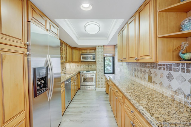 kitchen with open shelves, appliances with stainless steel finishes, a sink, light wood finished floors, and a tray ceiling