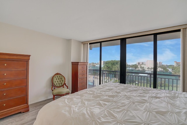 bedroom with baseboards, access to outside, and light wood-type flooring