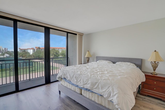bedroom featuring floor to ceiling windows, wood finished floors, and access to exterior