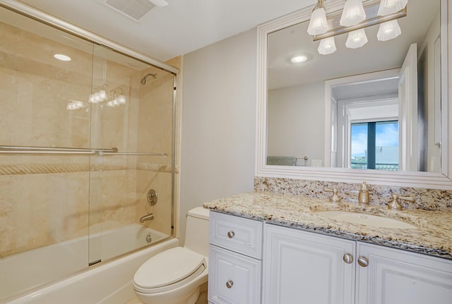 bathroom featuring toilet, visible vents, bath / shower combo with glass door, and vanity