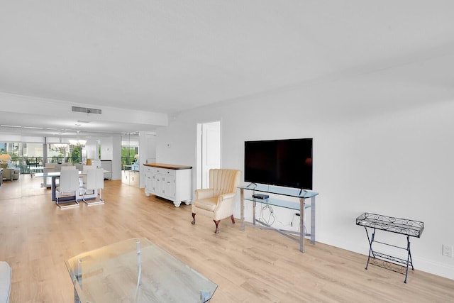 living room with light wood-style floors, baseboards, a notable chandelier, and visible vents
