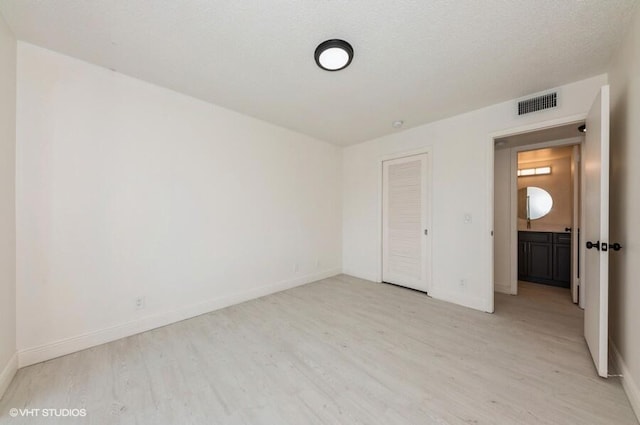 unfurnished bedroom with light wood-style flooring, baseboards, a closet, and visible vents
