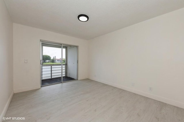 spare room with baseboards and light wood-style floors