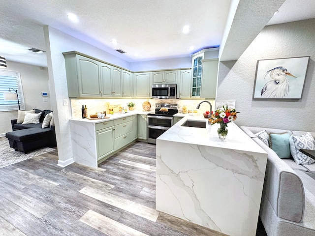 380 Laurie Rd, West Palm Beach, FL 33405 - kitchen with stainless steel appliances, a sink, light wood-style flooring, decorative backsplash, and light stone counters